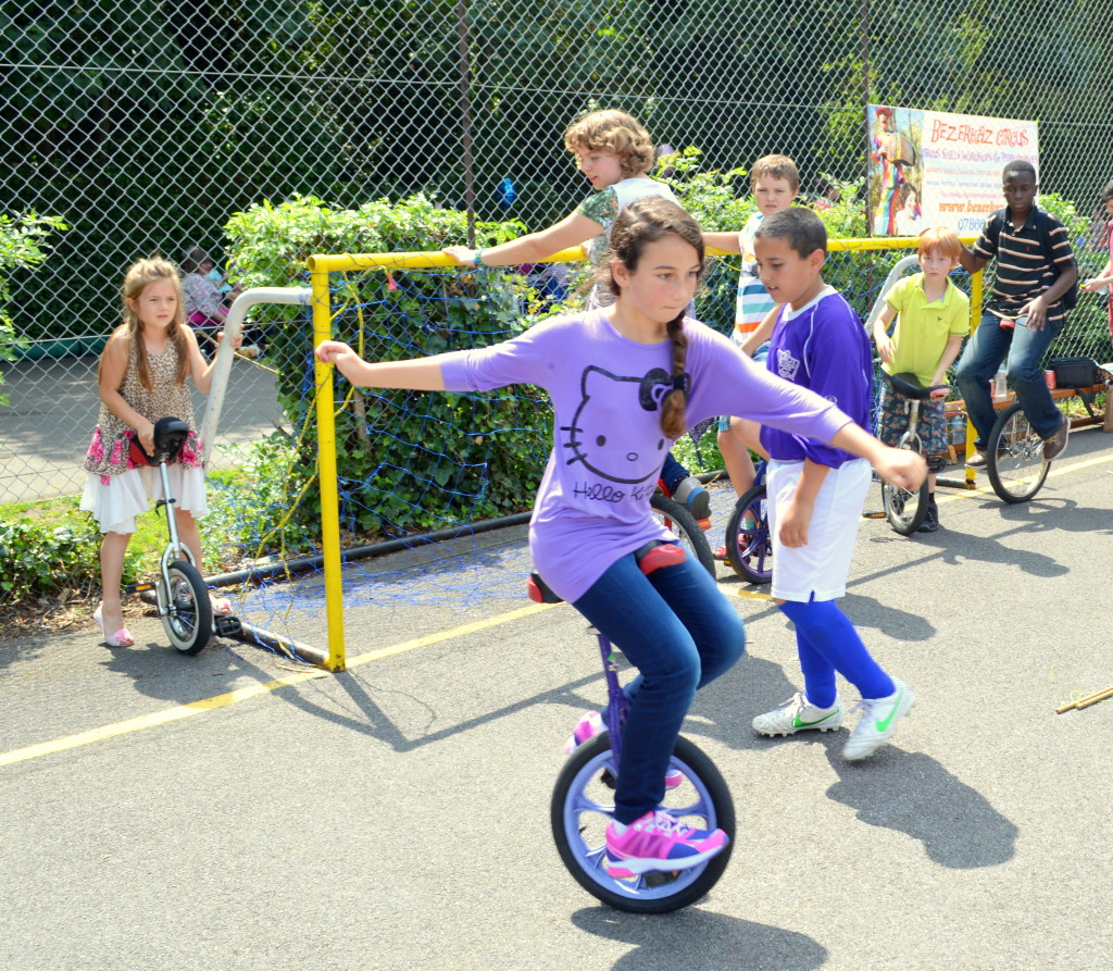 Girl riding unicycle in circus skills workshop at school fete, Wimbledon