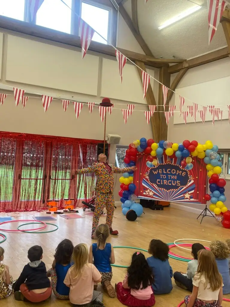 Circus performer balancing an item on his nose at circus themed birthday party in a beautifully decorated church hall in England
